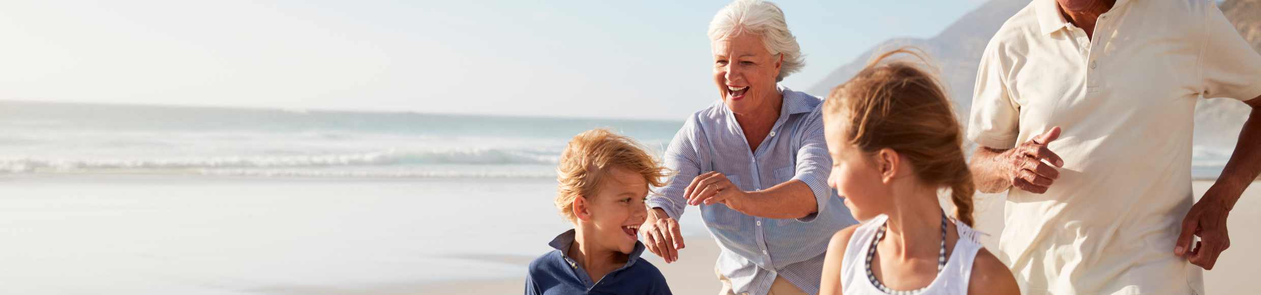 Image of an older couple and two children on the beach